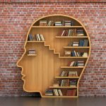 Concept of training. Wooden bookshelf full of books in form of man head on a bricks background. Science about human. Psychology. A human have more knowledge.